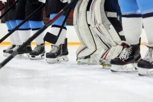 Focused view of hockey players' skates and sticks on an ice rink, ready for action.