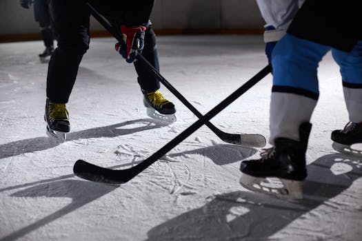 Close-up of hockey players battling for puck during an intense face-off on a lighted ice rink.