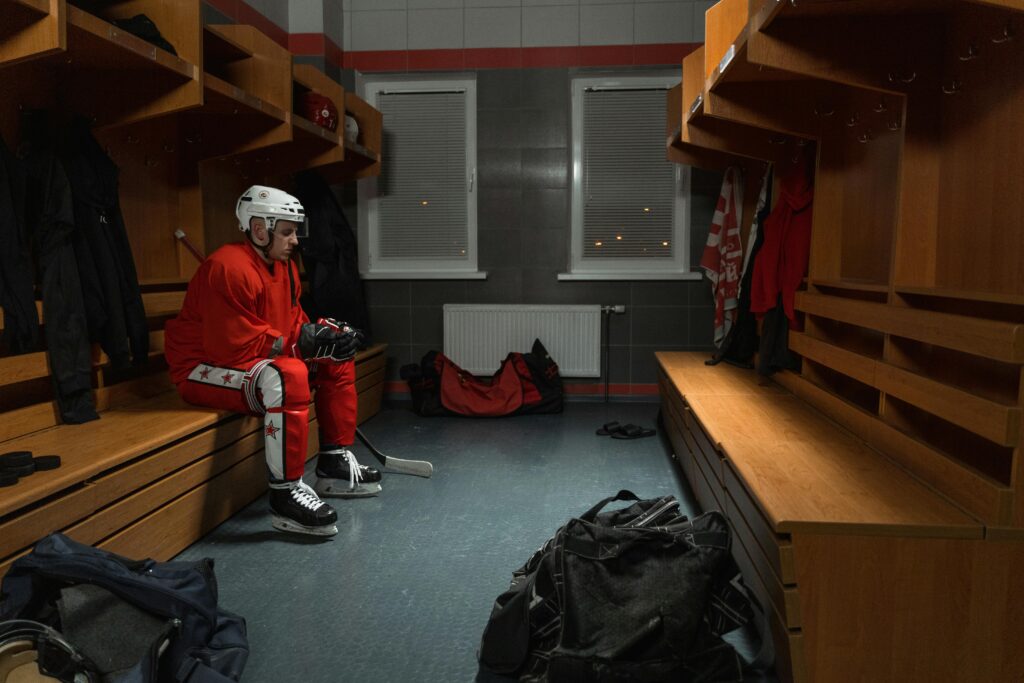 A focused hockey player in full gear sits in the locker room before a game.